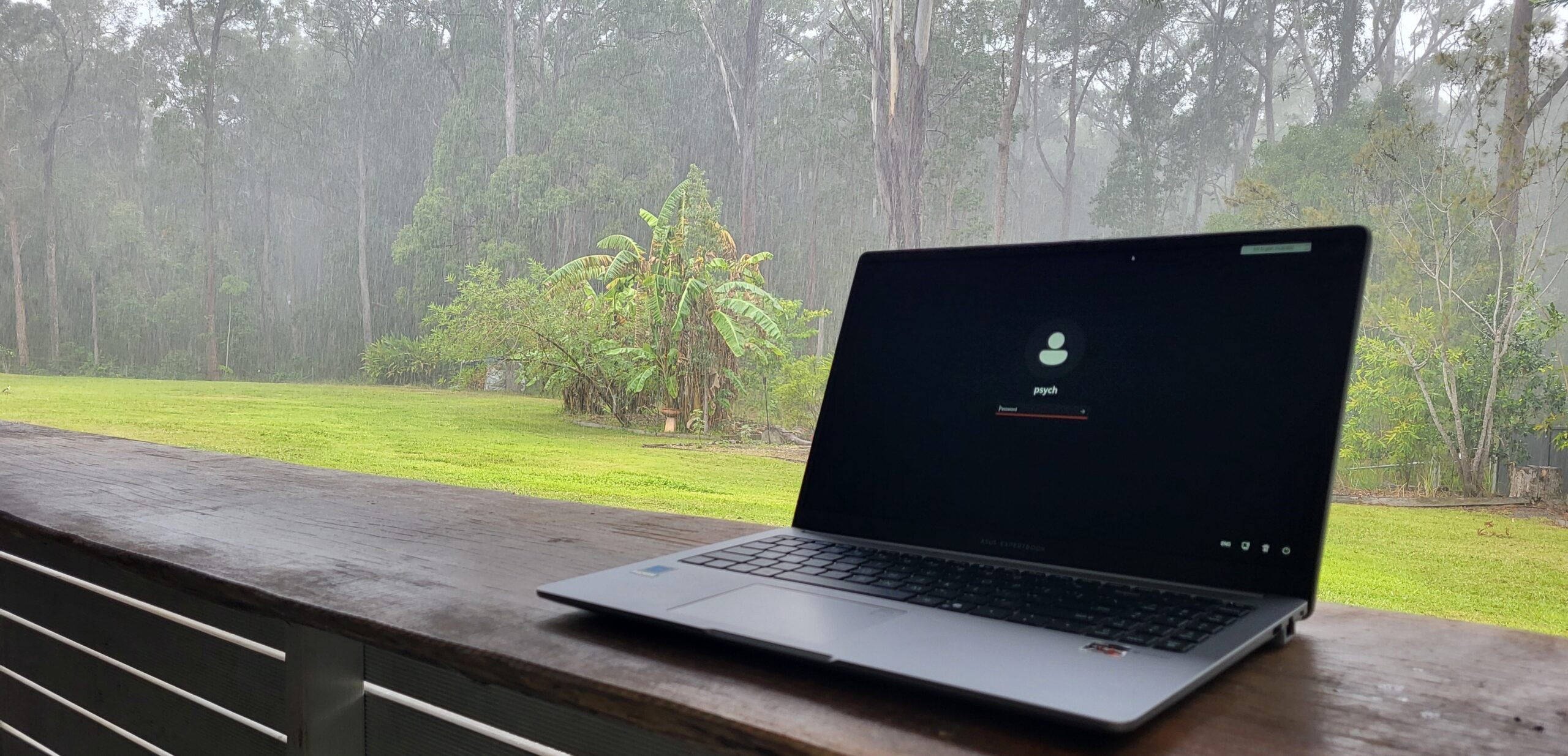 Laptop on an outdoor counter during rainy weather, accompanying a reflection on recovery-oriented practice.